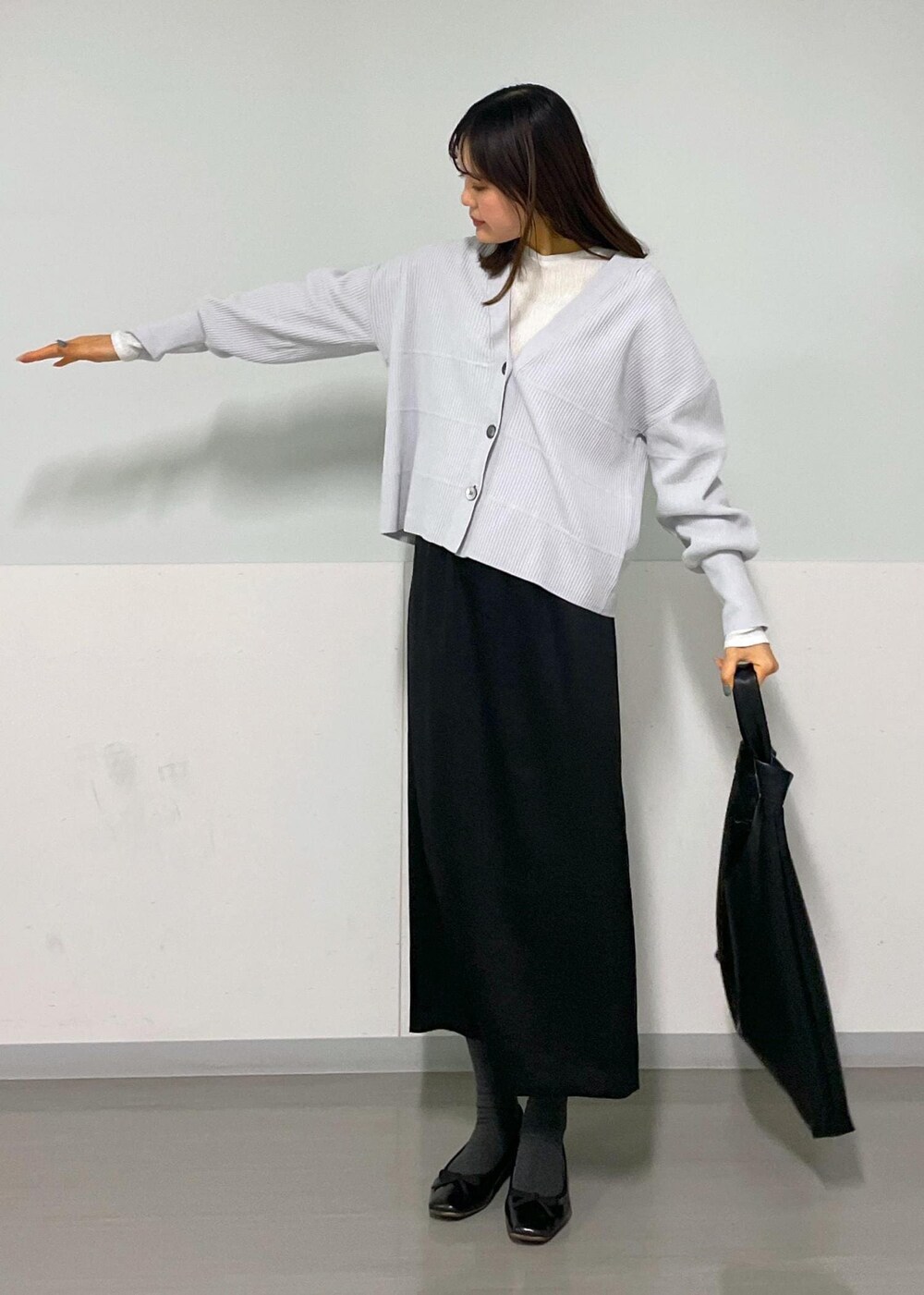 ブラック系のトートバッグ、ホワイト系のTシャツ/カットソー、グレー系のカーディガン/ボレロを着用したレディースの冬コーディネートの4枚目の写真