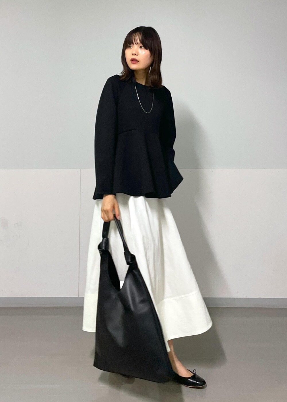 ブラック系のバレエシューズ、ホワイト系のスカート、ブラック系のTシャツ/カットソーを着用したレディースの秋コーディネートの2枚目の写真