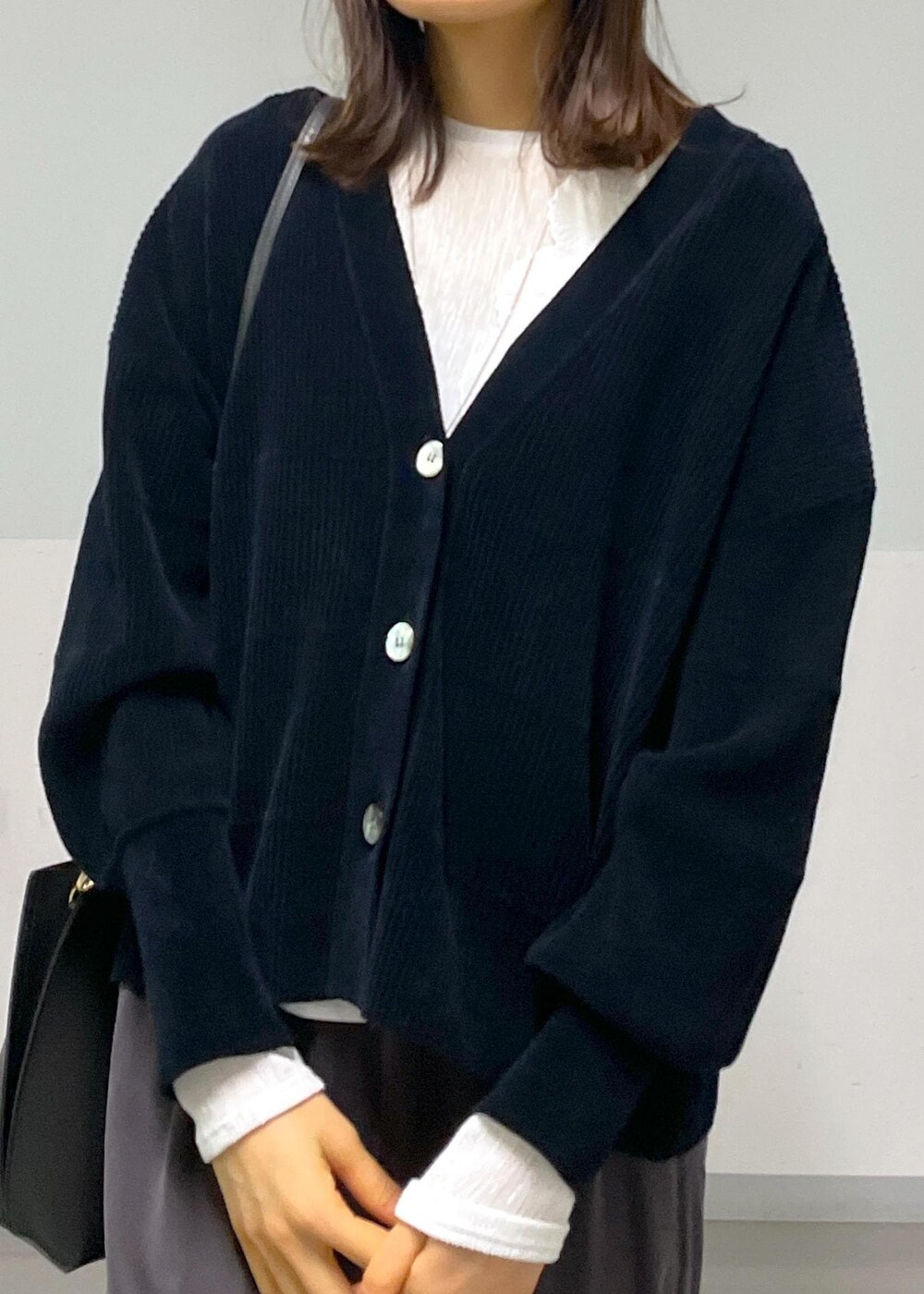 グレー系のスカート、ブラック系のカーディガン/ボレロ、ホワイト系のTシャツ/カットソーを着用したレディースの冬コーディネートの10枚目の写真