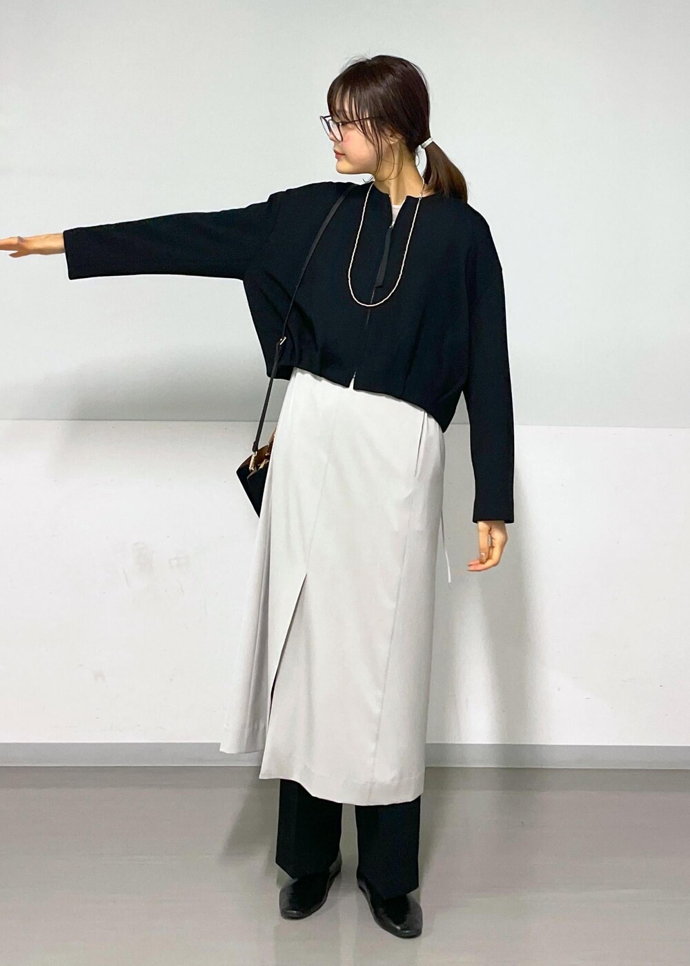 ベージュ系のジャンパースカート、ブラック系のブルゾン、ブラック系のスラックスを着用したレディースの春コーディネートの9枚目の写真