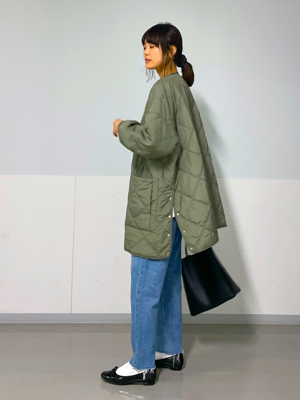 グリーン系のブルゾン、ブルー系のデニムパンツ、ブラック系のバレエシューズを着用したレディースの秋コーディネートの2枚目の写真