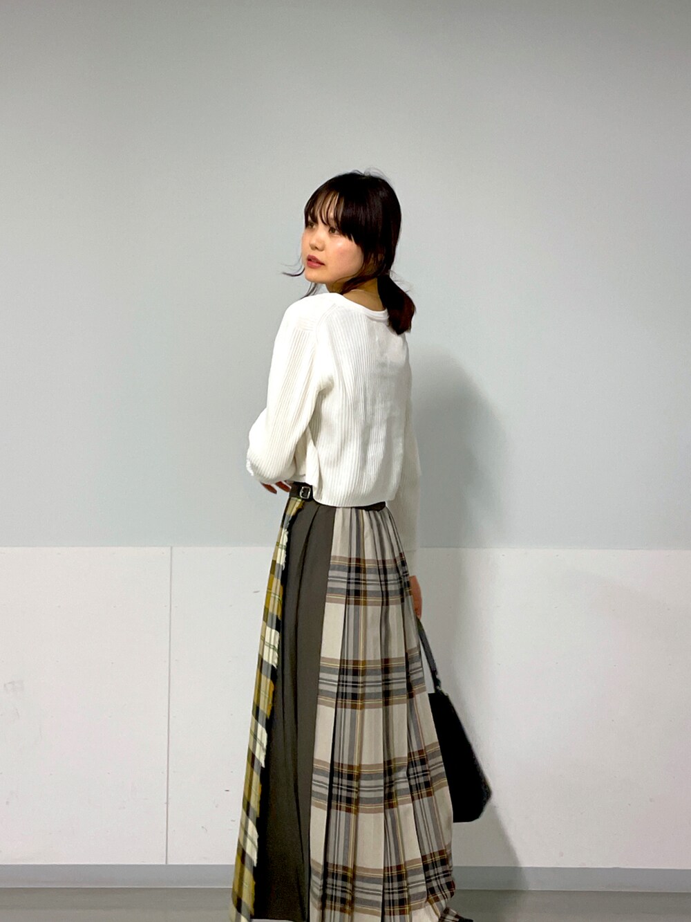 ホワイト系のカーディガン/ボレロ、イエロー系のスカート、ベージュ系のスニーカーを着用したレディースの秋コーディネートの3枚目の写真