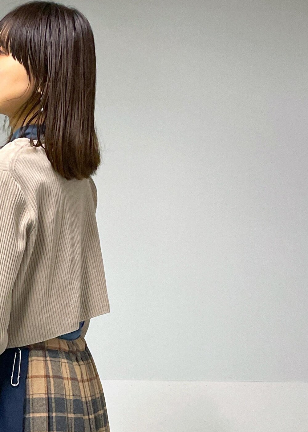 ブルー系のTシャツ/カットソー、ベージュ系のスカート、グレー系のカーディガン/ボレロを着用したレディースの秋コーディネートの9枚目の写真