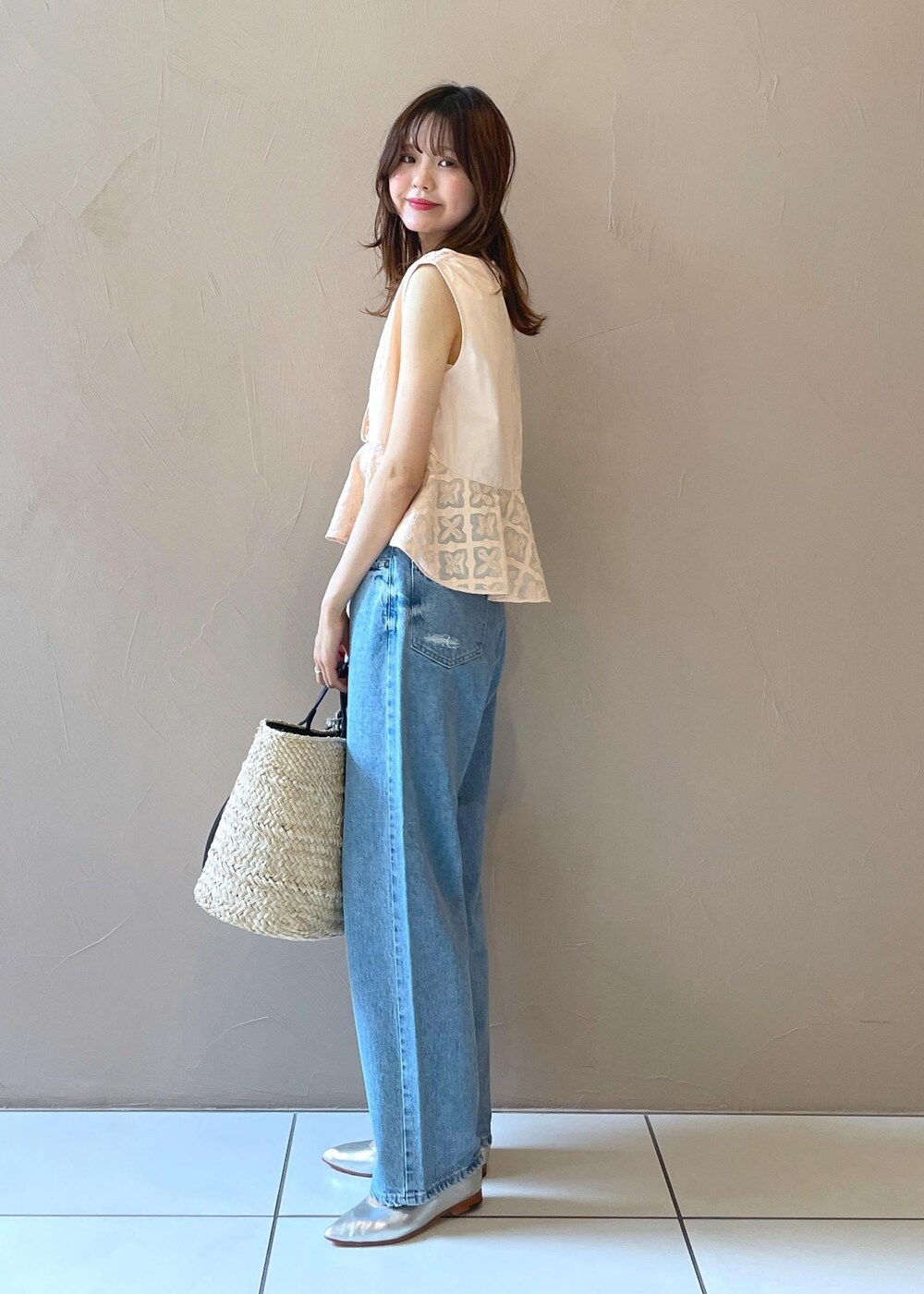 ホワイト系のかごバッグ、ブルー系のデニムパンツ、シルバー系のパンプスを着用したレディースの夏コーディネートの3枚目の写真