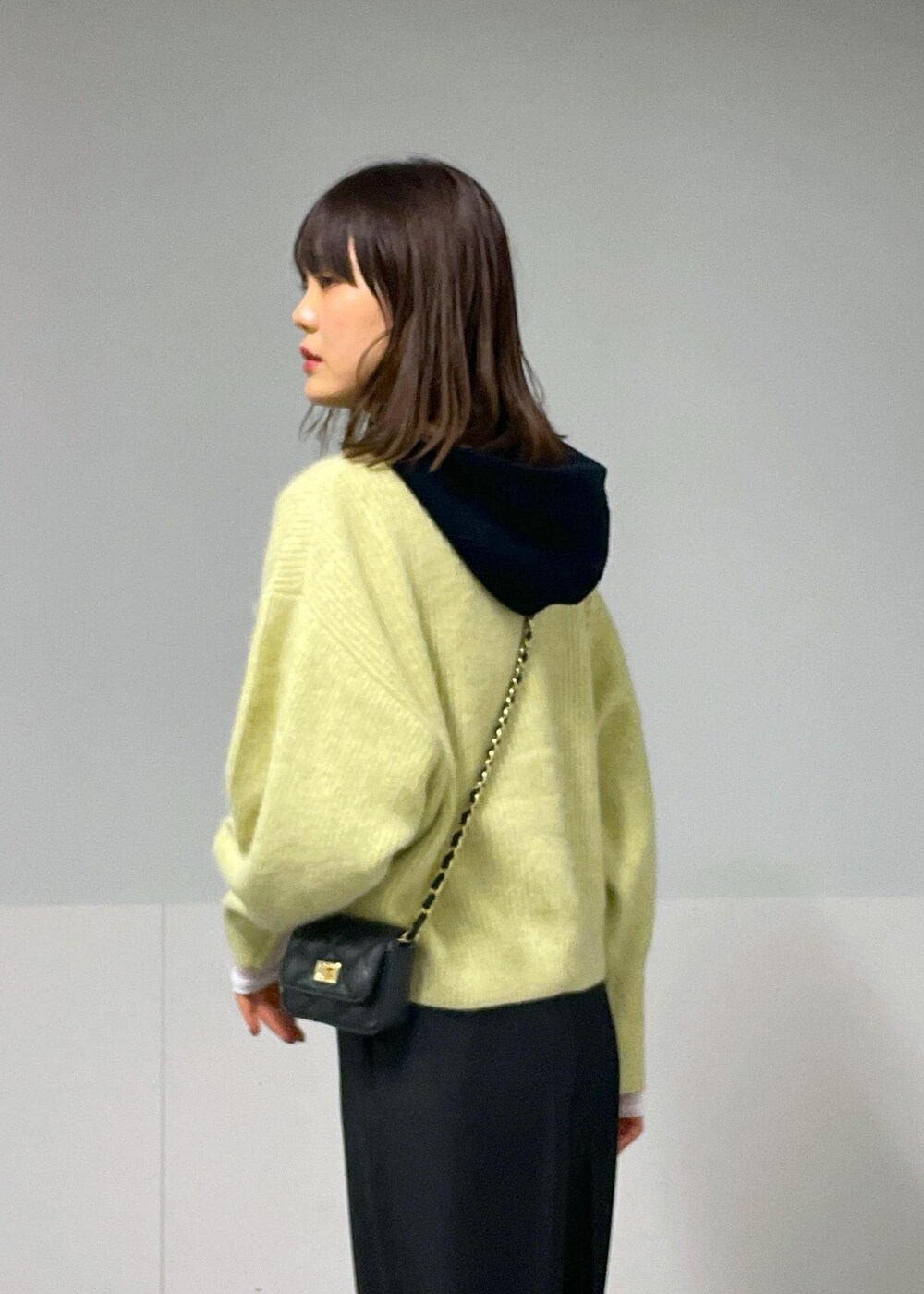 ブラック系のショルダーバッグ、イエロー系のニット/セーター、ホワイト系のTシャツ/カットソーを着用したレディースの秋コーディネートの7枚目の写真