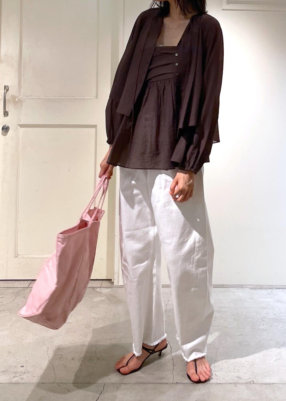 グレー系のタンクトップ、ブラック系のサンダル、ホワイト系のデニムパンツを着用したレディースの夏コーディネートの6枚目の写真