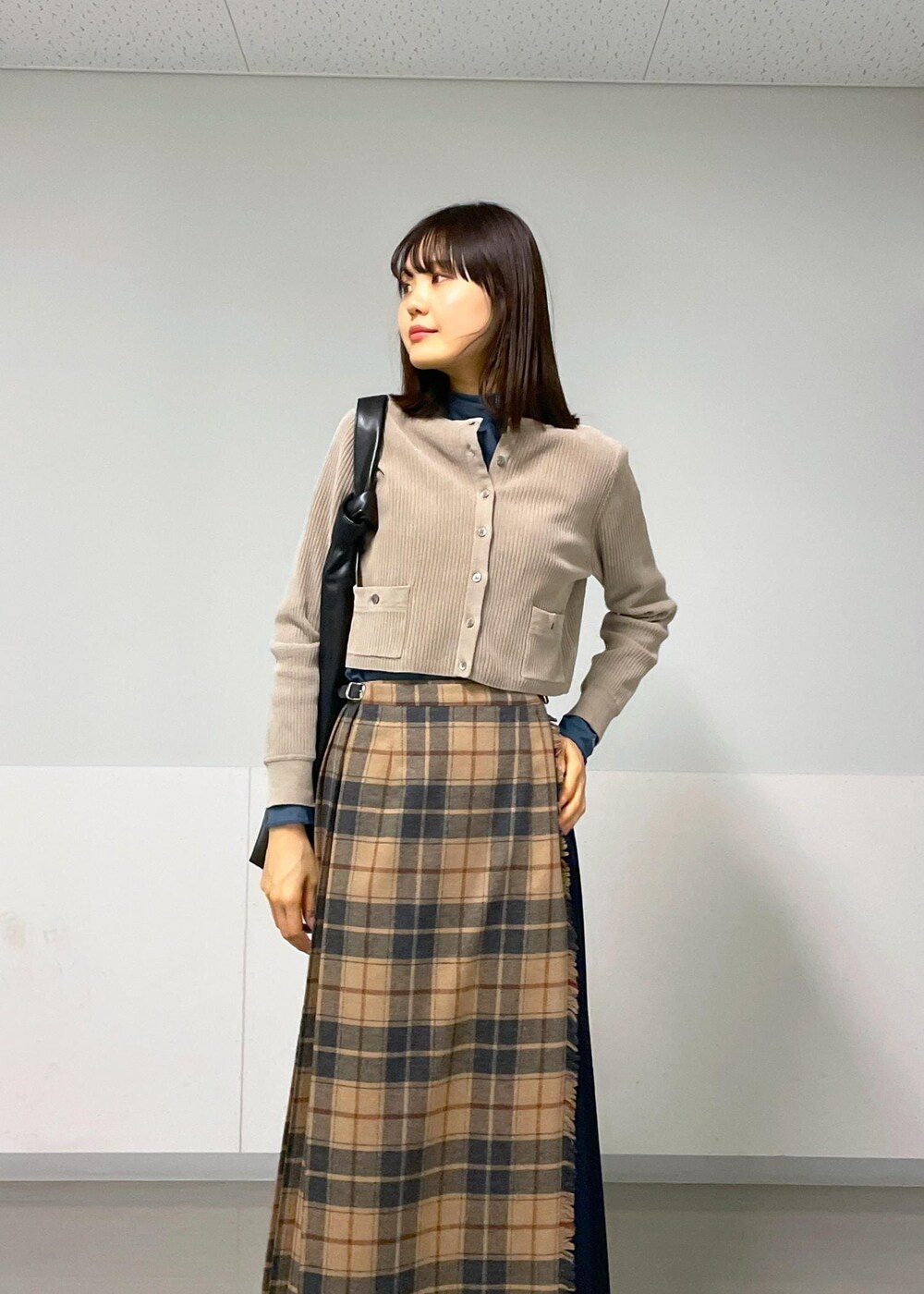 ブルー系のTシャツ/カットソー、ベージュ系のスカート、グレー系のカーディガン/ボレロを着用したレディースの秋コーディネートの6枚目の写真