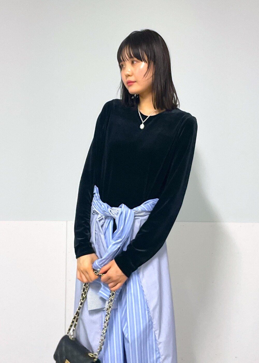 ブラック系のショルダーバッグ、ブルー系のシャツワンピース、ホワイト系のネックレスを着用したレディースの秋コーディネートの4枚目の写真