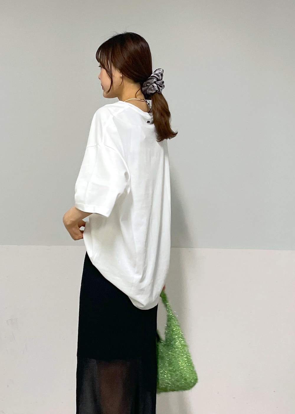 ブラック系のスカート、グリーン系のハンドバッグ、ホワイト系のTシャツ/カットソーを着用したレディースの夏コーディネートの5枚目の写真