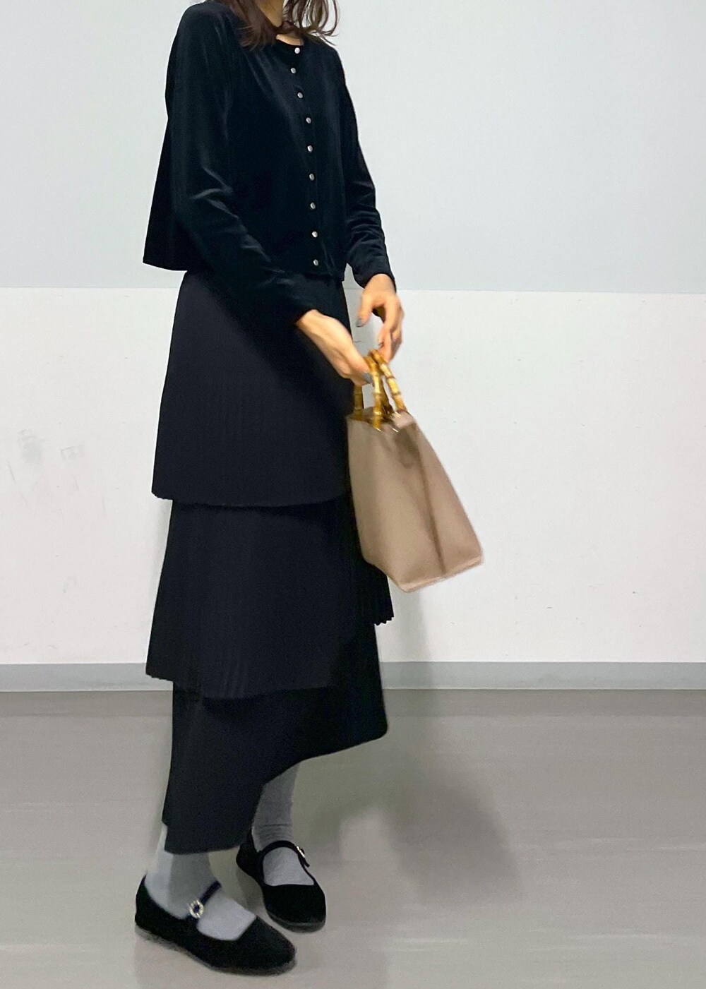 ブラック系のカーディガン/ボレロ、ブラック系のスカート、ベージュ系のハンドバッグを着用したレディースの冬コーディネートの8枚目の写真