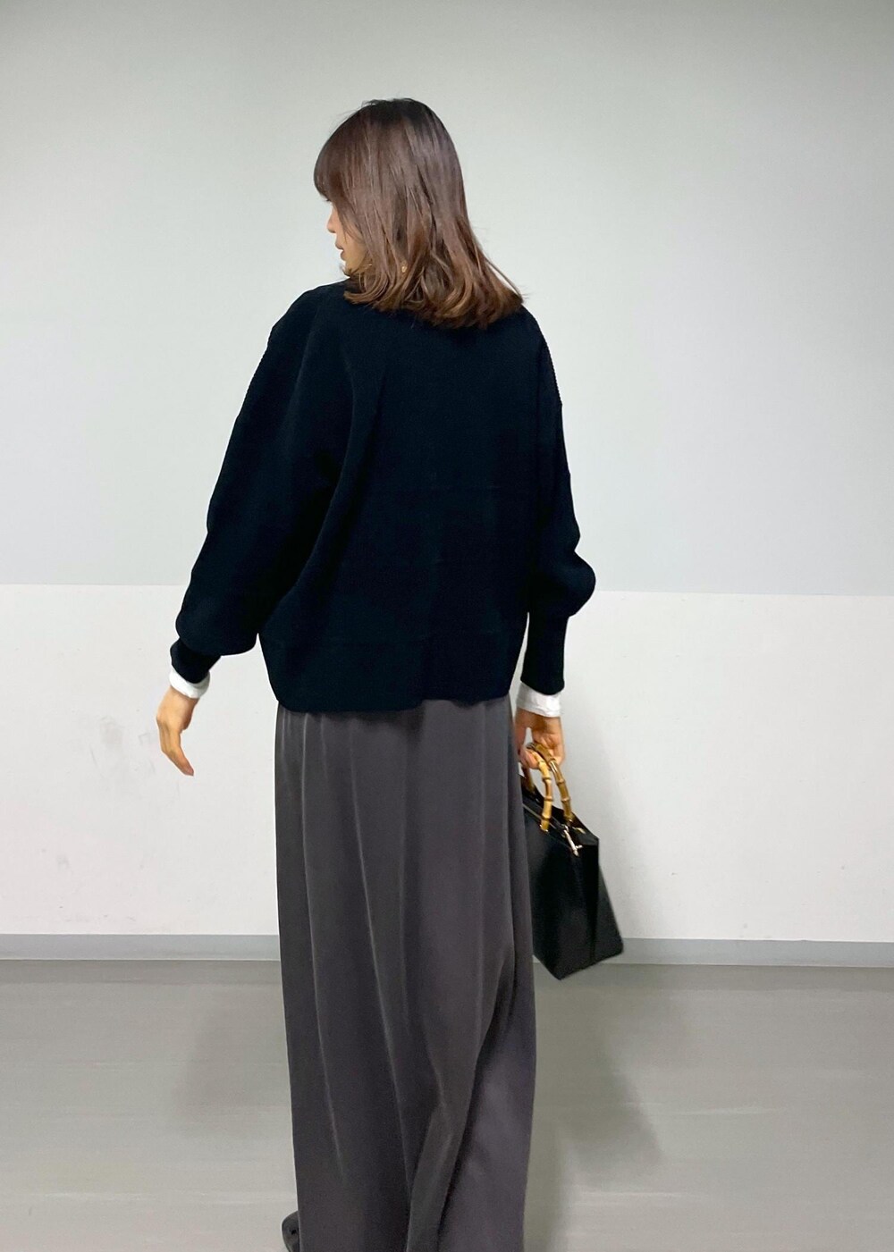 グレー系のスカート、ブラック系のカーディガン/ボレロ、ホワイト系のTシャツ/カットソーを着用したレディースの冬コーディネートの5枚目の写真