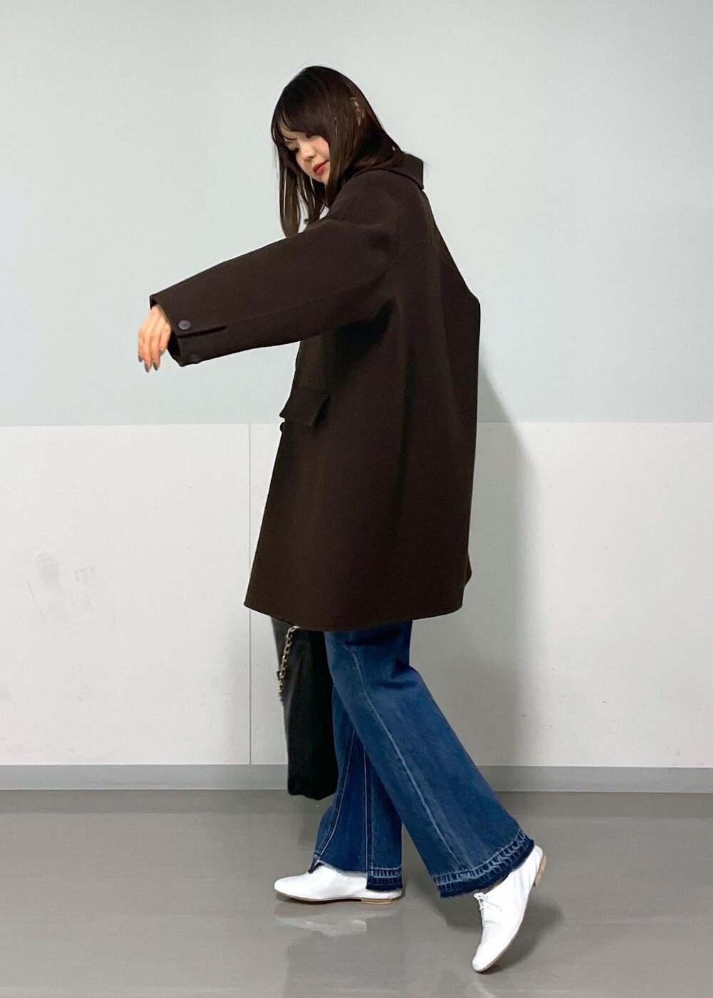 ブラウン系のピーコート、ブラック系のトートバッグ、ブラウン系のTシャツ/カットソーを着用したレディースの冬コーディネートの3枚目の写真