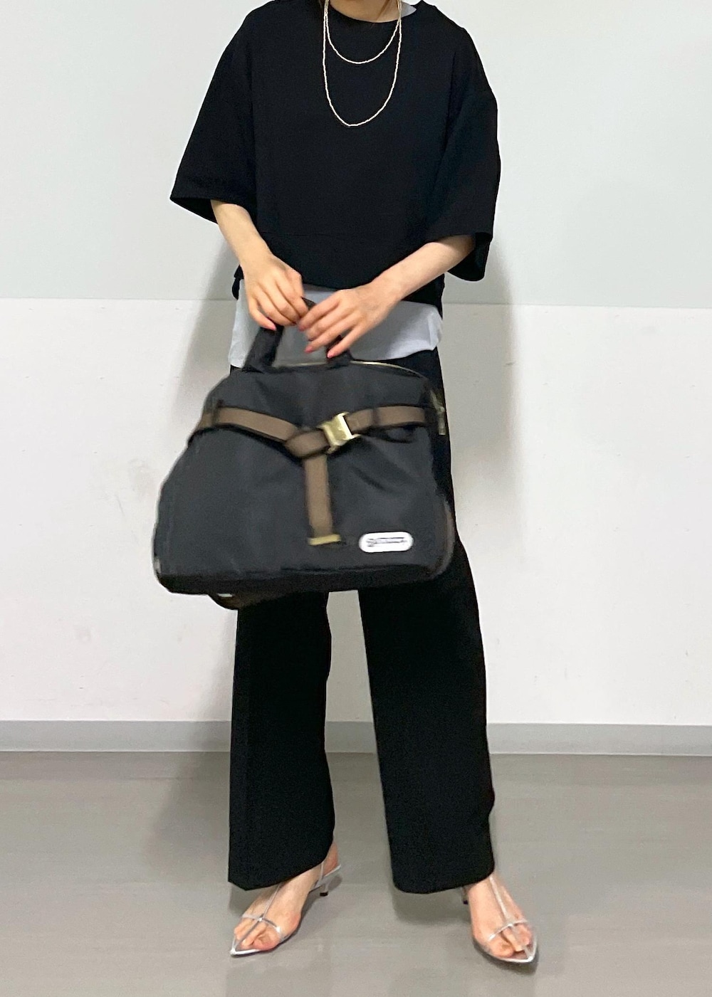 ブラック系のスラックス、シルバー系のサンダル、ブラック系のトートバッグを着用したレディースの夏コーディネートの7枚目の写真