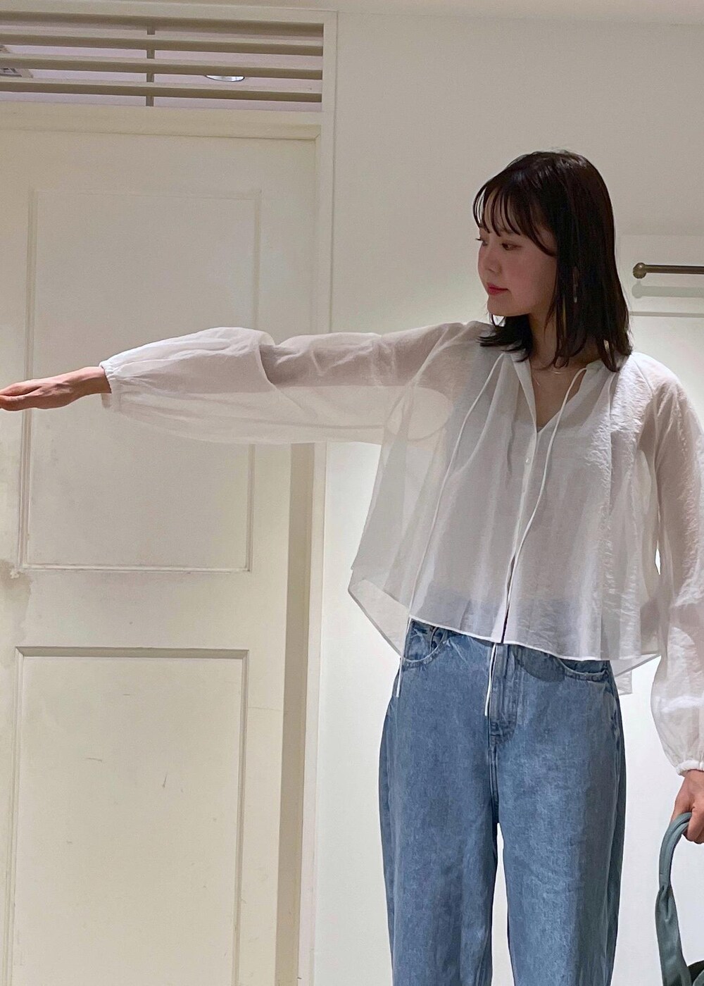 グレー系のタンクトップ、ホワイト系のシャツ/ブラウス、ブルー系のデニムパンツを着用したレディースの夏コーディネートの5枚目の写真