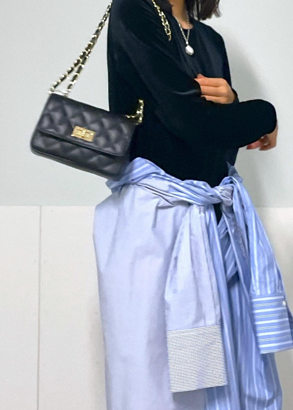 ブラック系のショルダーバッグ、ブルー系のシャツワンピース、ホワイト系のネックレスを着用したレディースの秋コーディネートの5枚目の写真