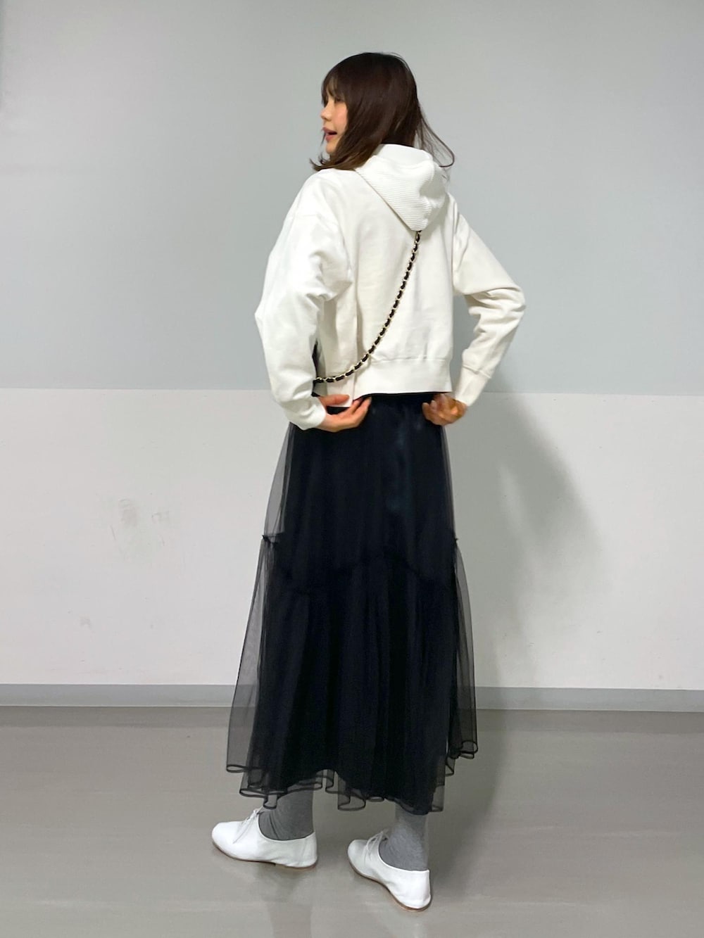 ブラック系のショルダーバッグ、ホワイト系のニット/セーター、ブラック系のスカートを着用したレディースの冬コーディネートの2枚目の写真