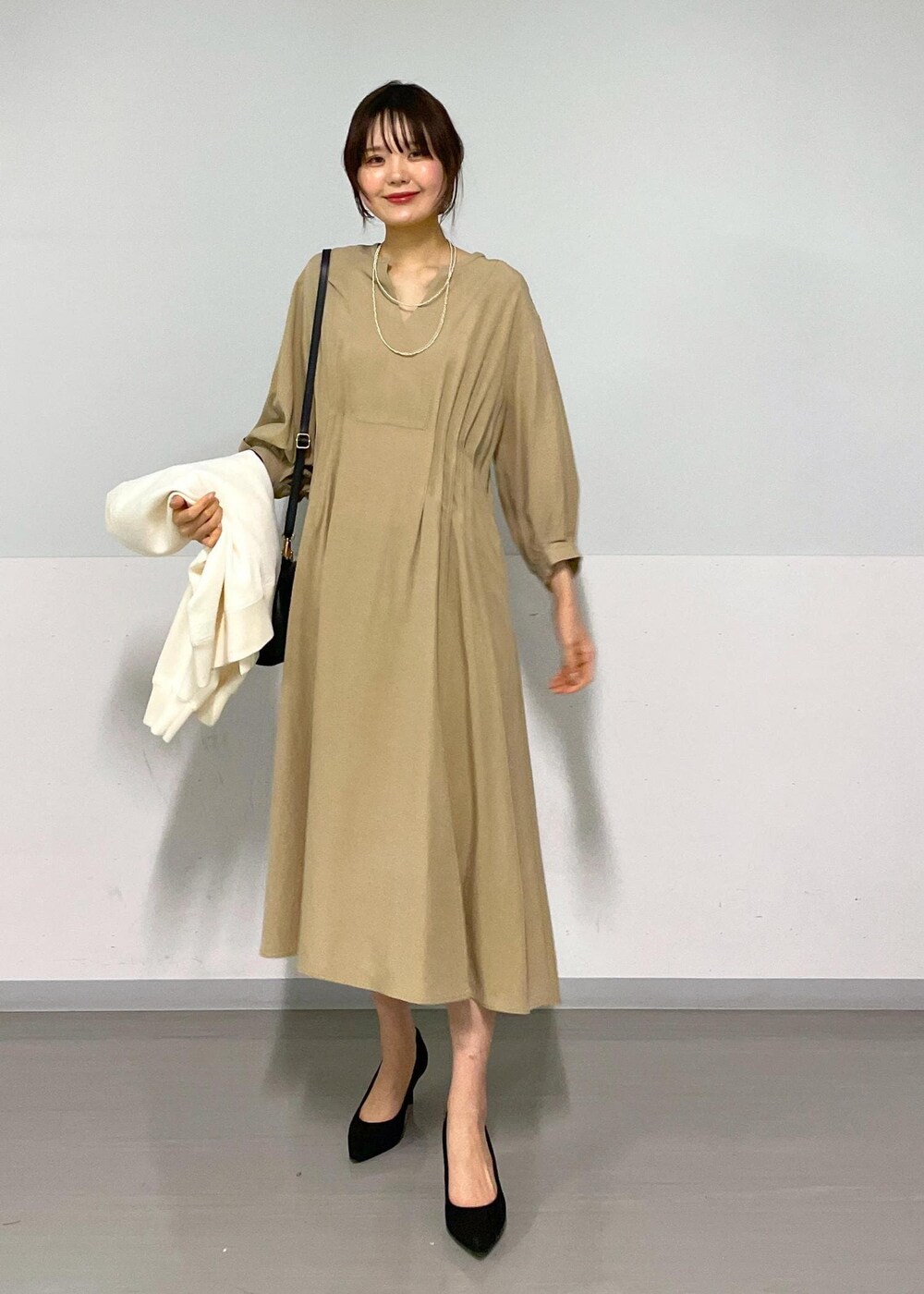 ブラック系のショルダーバッグ、ベージュ系のワンピース、ホワイト系のカーディガン/ボレロを着用したレディースの春コーディネートの10枚目の写真