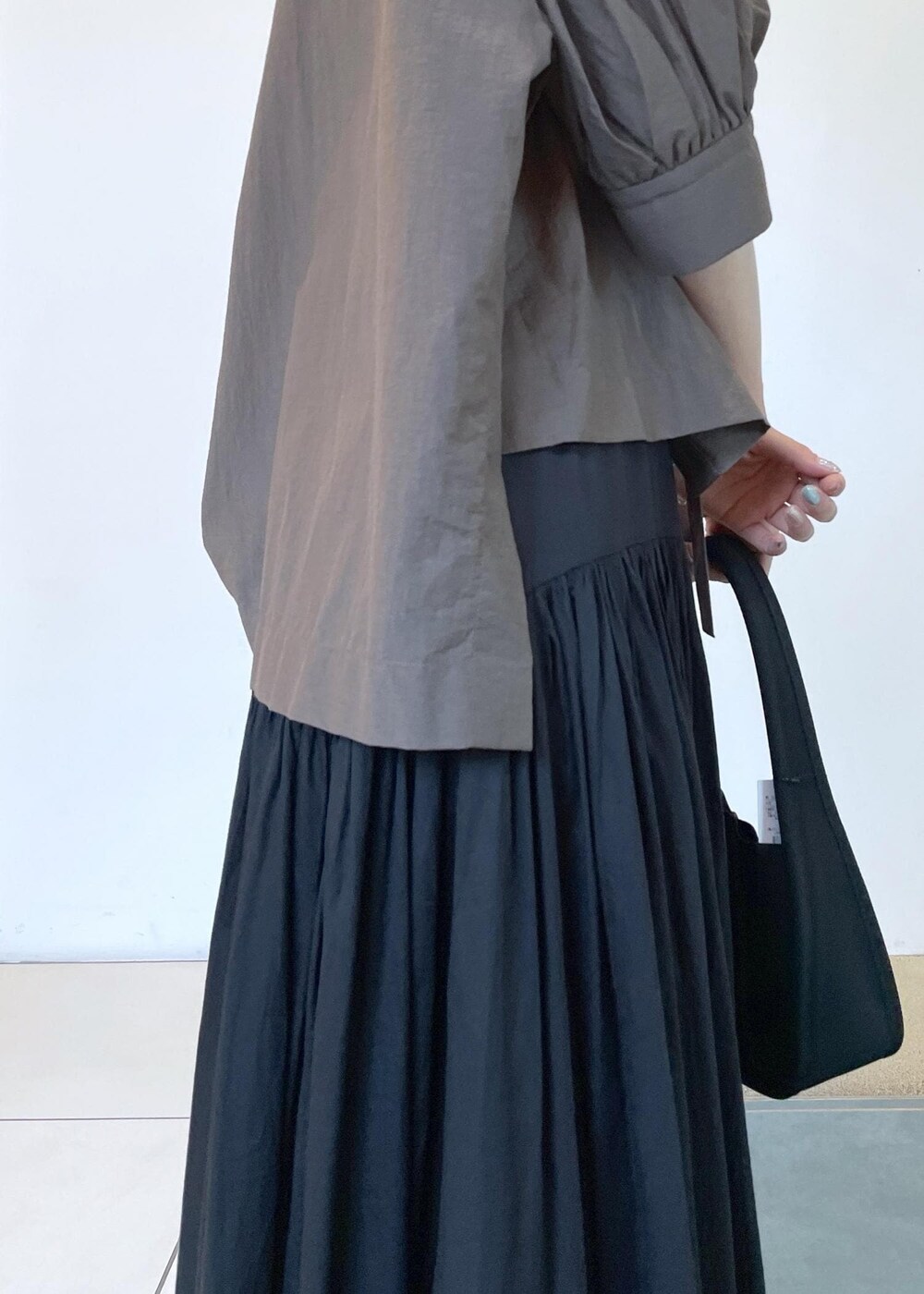 ブラック系のサンダル、ブラック系のスカート、ブラック系のハンドバッグを着用したレディースの夏コーディネートの5枚目の写真