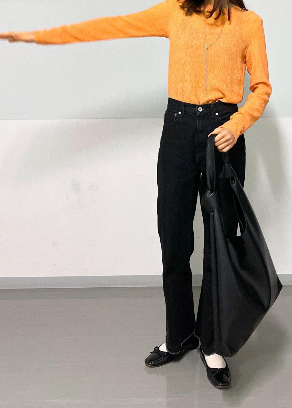 ブラック系のトートバッグ、グレー系のデニムパンツ、オレンジ系のTシャツ/カットソーを着用したレディースの冬コーディネートの5枚目の写真