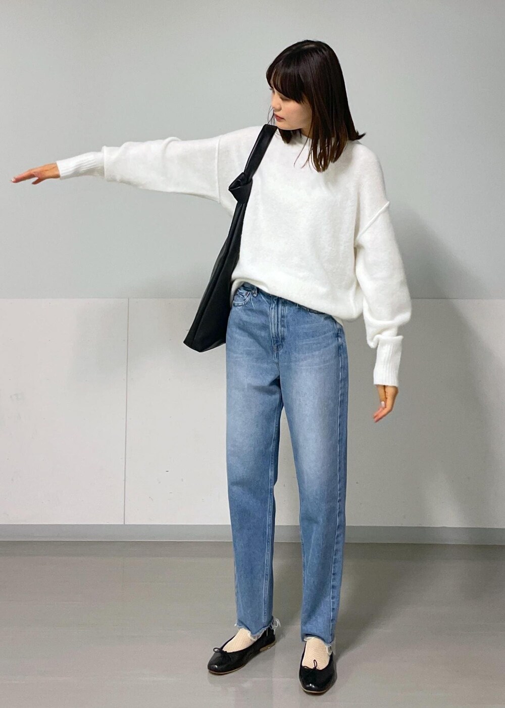 ブラック系のバレエシューズ、ブルー系のデニムパンツ、ホワイト系のニット/セーターを着用したレディースの秋コーディネートの5枚目の写真