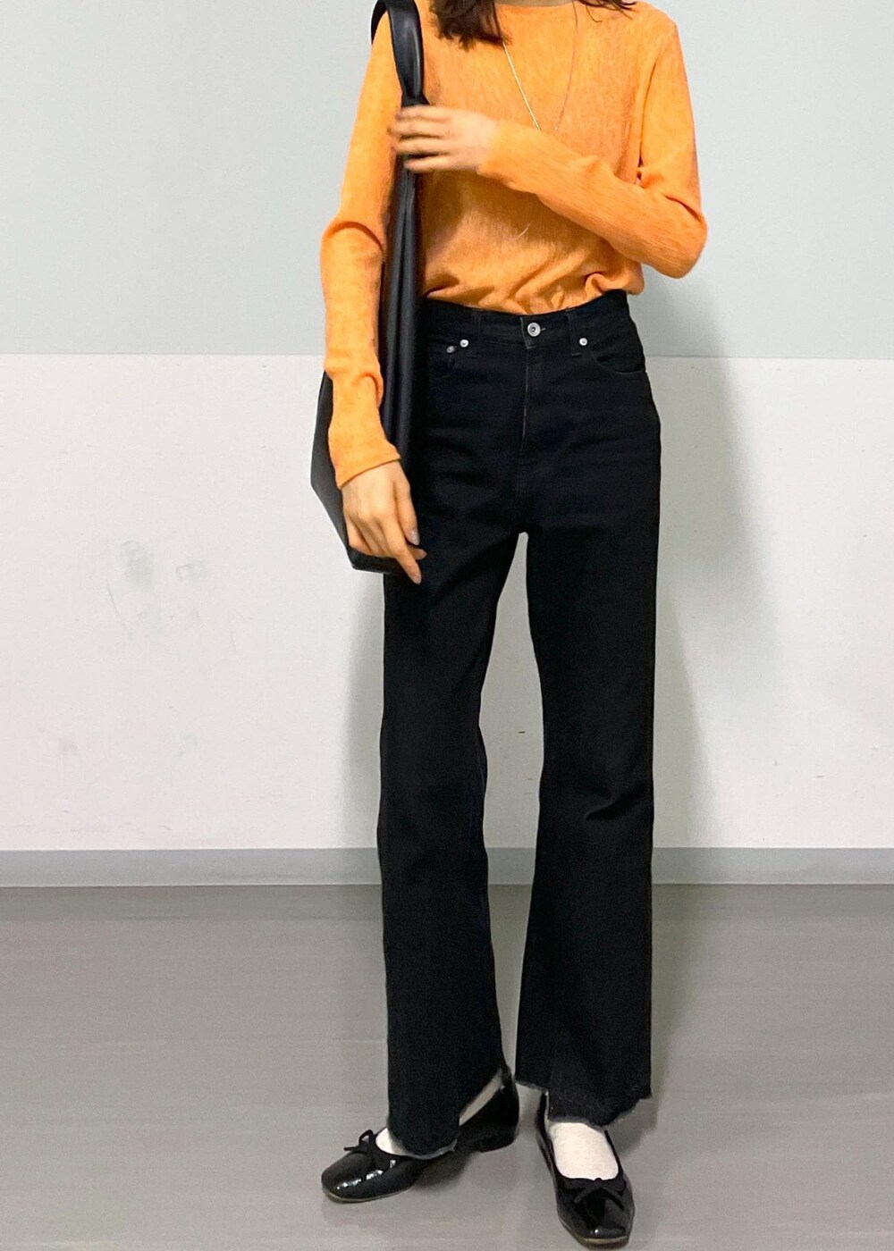 ブラック系のトートバッグ、グレー系のデニムパンツ、オレンジ系のTシャツ/カットソーを着用したレディースの冬コーディネートの4枚目の写真