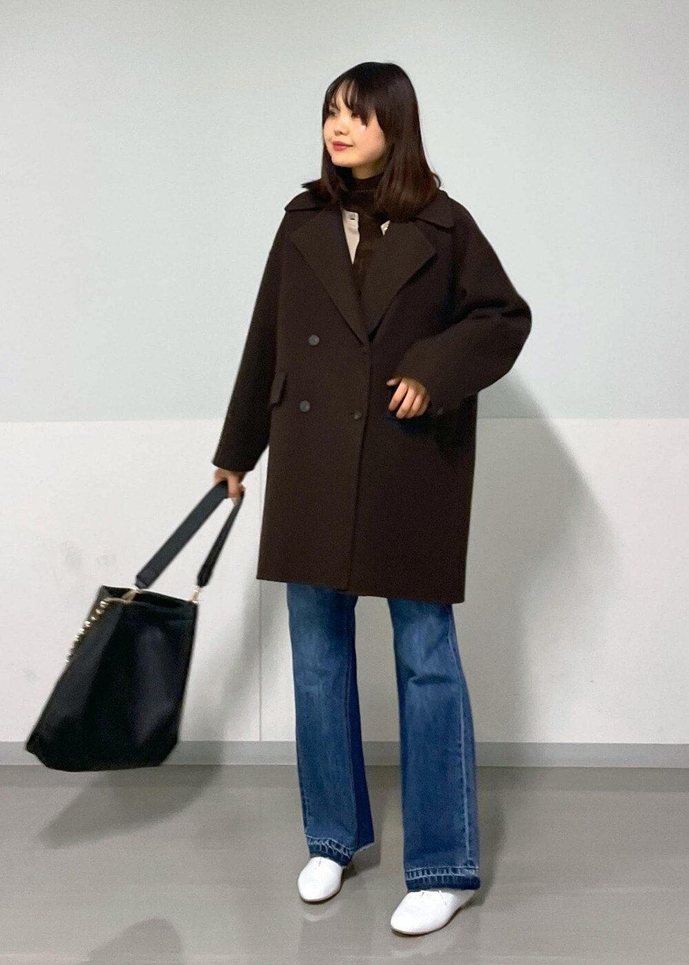ブラウン系のピーコート、ブラック系のトートバッグ、ブラウン系のTシャツ/カットソーを着用したレディースの冬コーディネートの9枚目の写真