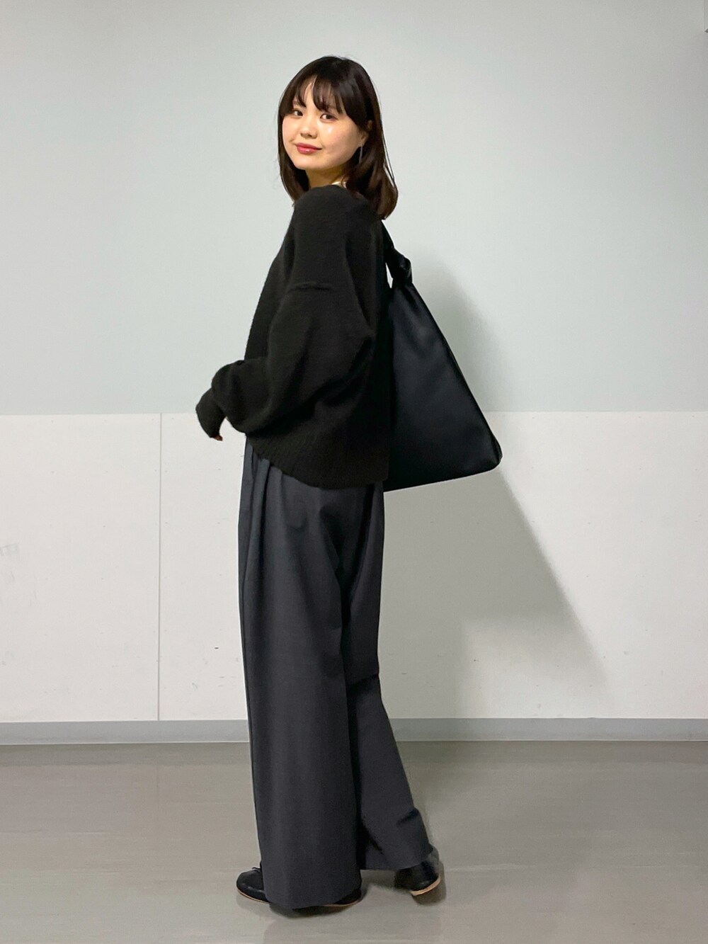 ブラウン系のニット/セーター、グレー系のスラックス、ブラック系のパンプスを着用したレディースの秋コーディネートの3枚目の写真