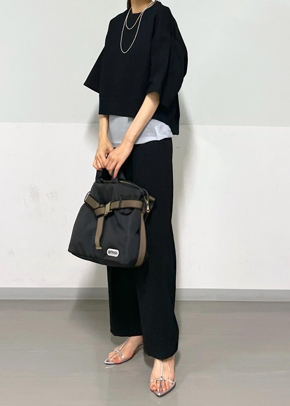 ブラック系のスラックス、シルバー系のサンダル、ブラック系のトートバッグを着用したレディースの夏コーディネートの2枚目の写真
