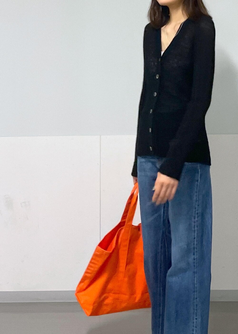 グレー系のタンクトップ、ブラック系のカーディガン/ボレロ、ブルー系のデニムパンツを着用したレディースの秋コーディネートの5枚目の写真