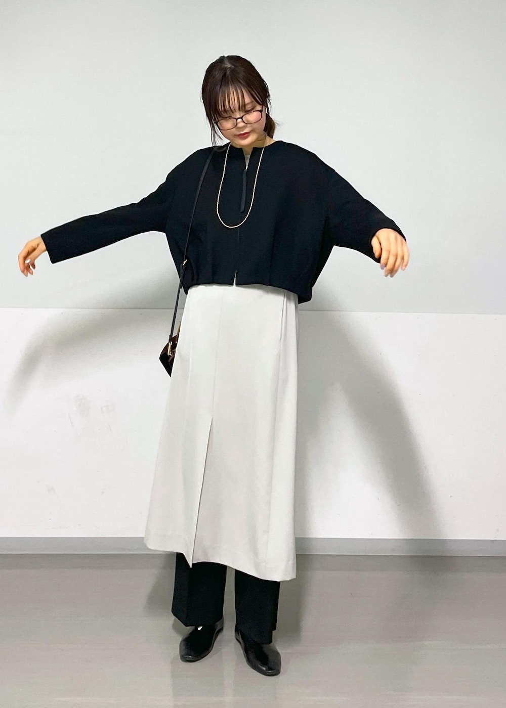 ベージュ系のジャンパースカート、ブラック系のブルゾン、ブラック系のスラックスを着用したレディースの春コーディネートの8枚目の写真