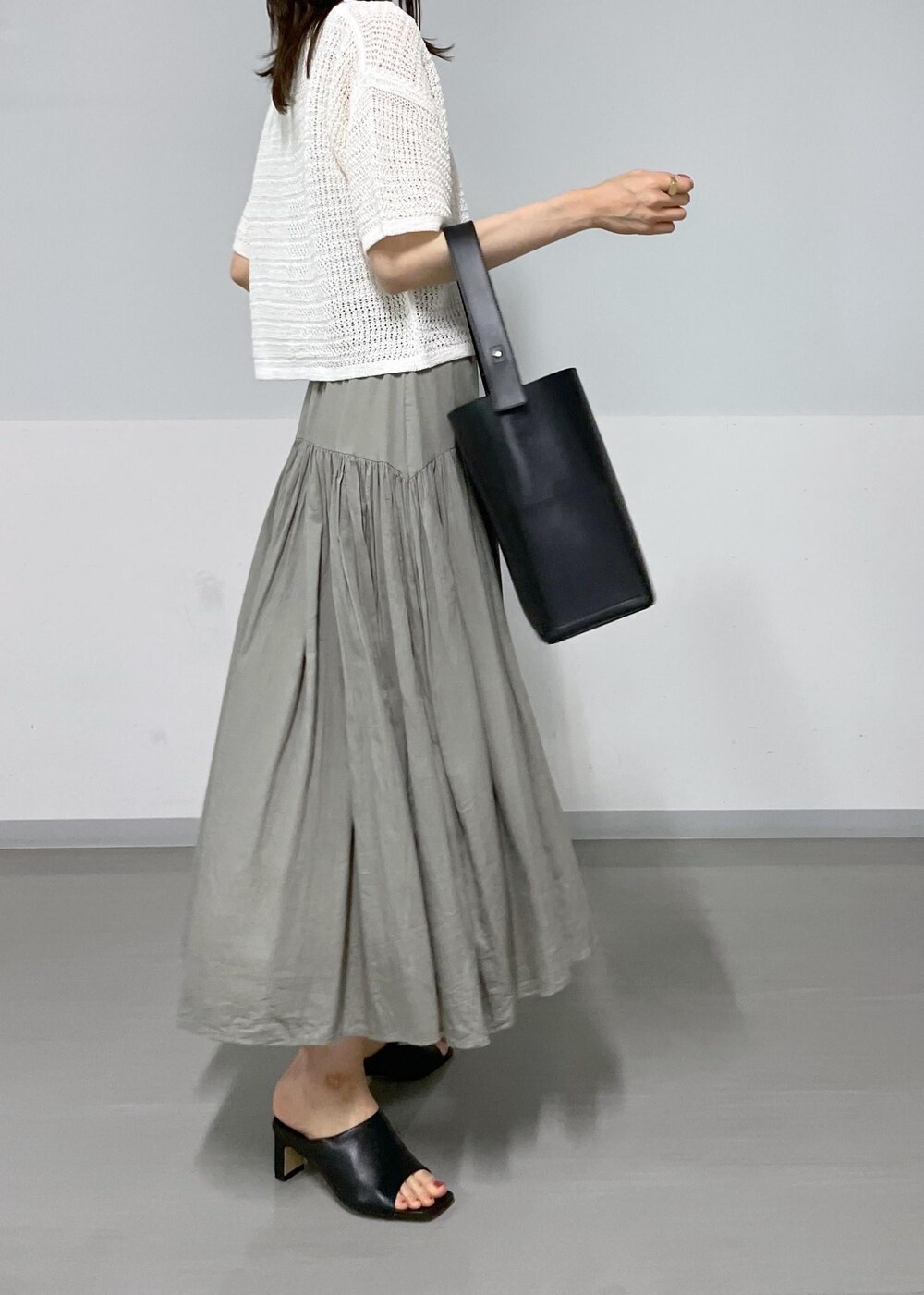 ブラック系のサンダル、ブラック系のトートバッグ、グレー系のスカートを着用したレディースの春コーディネートの6枚目の写真