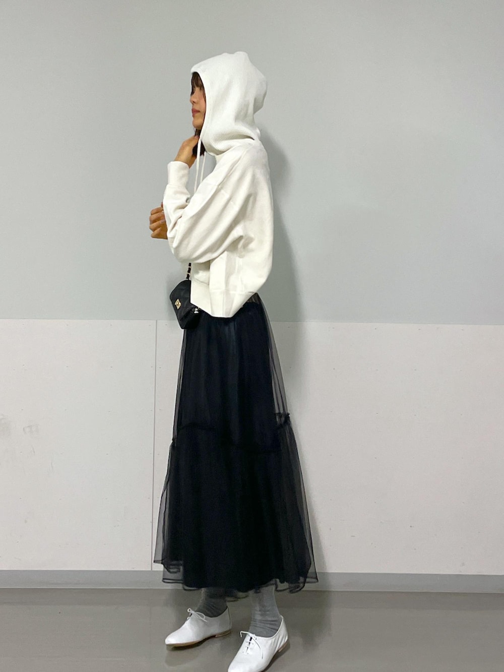 ブラック系のショルダーバッグ、ホワイト系のニット/セーター、ブラック系のスカートを着用したレディースの冬コーディネートの5枚目の写真