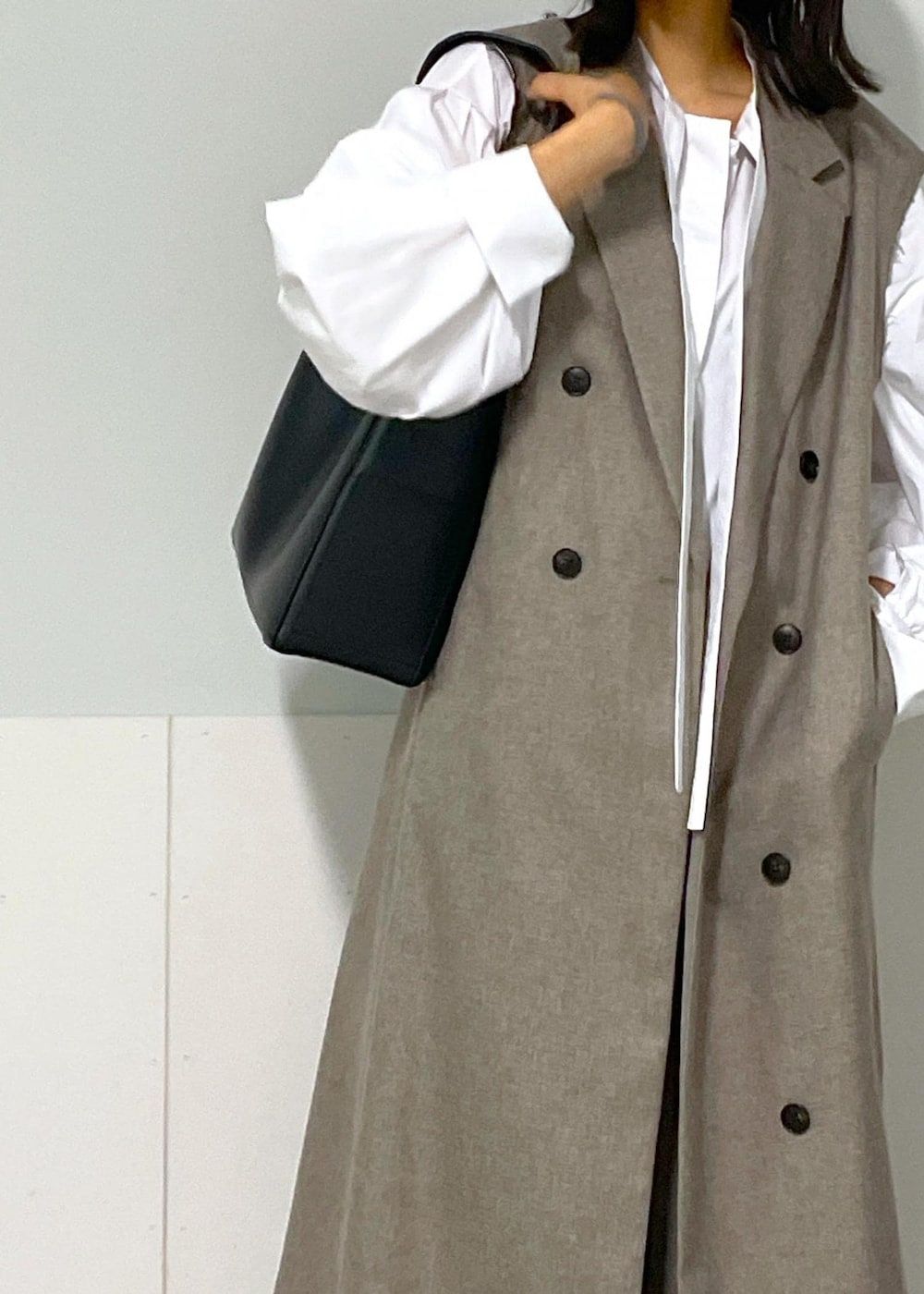 ベージュ系のスラックス、ベージュ系のジャンパースカート、ホワイト系のシャツ/ブラウスを着用したレディースの秋コーディネートの4枚目の写真