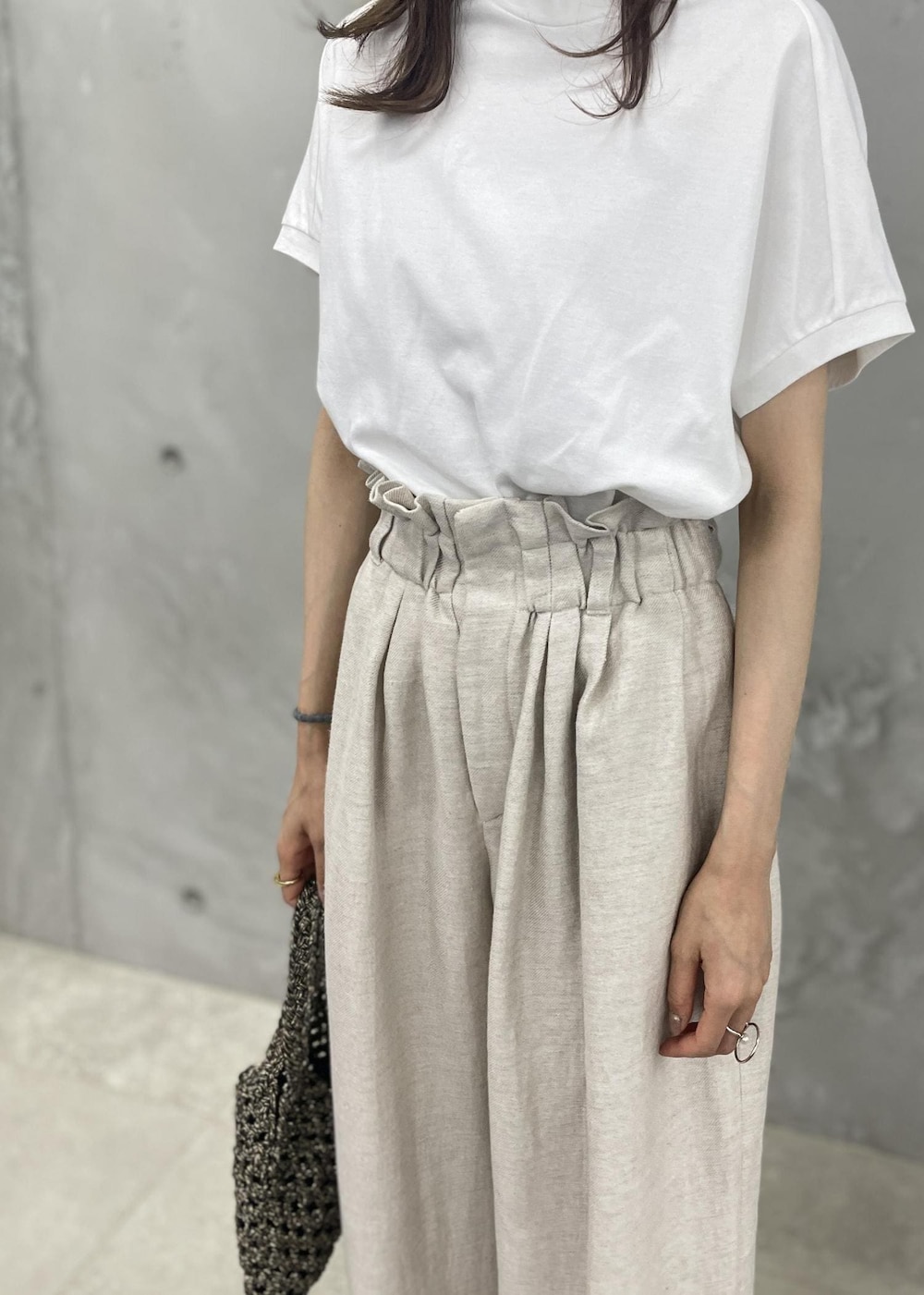 ブラック系のサンダル、ホワイト系のスラックス、ブラック系のハンドバッグを着用したレディースの春コーディネートの3枚目の写真