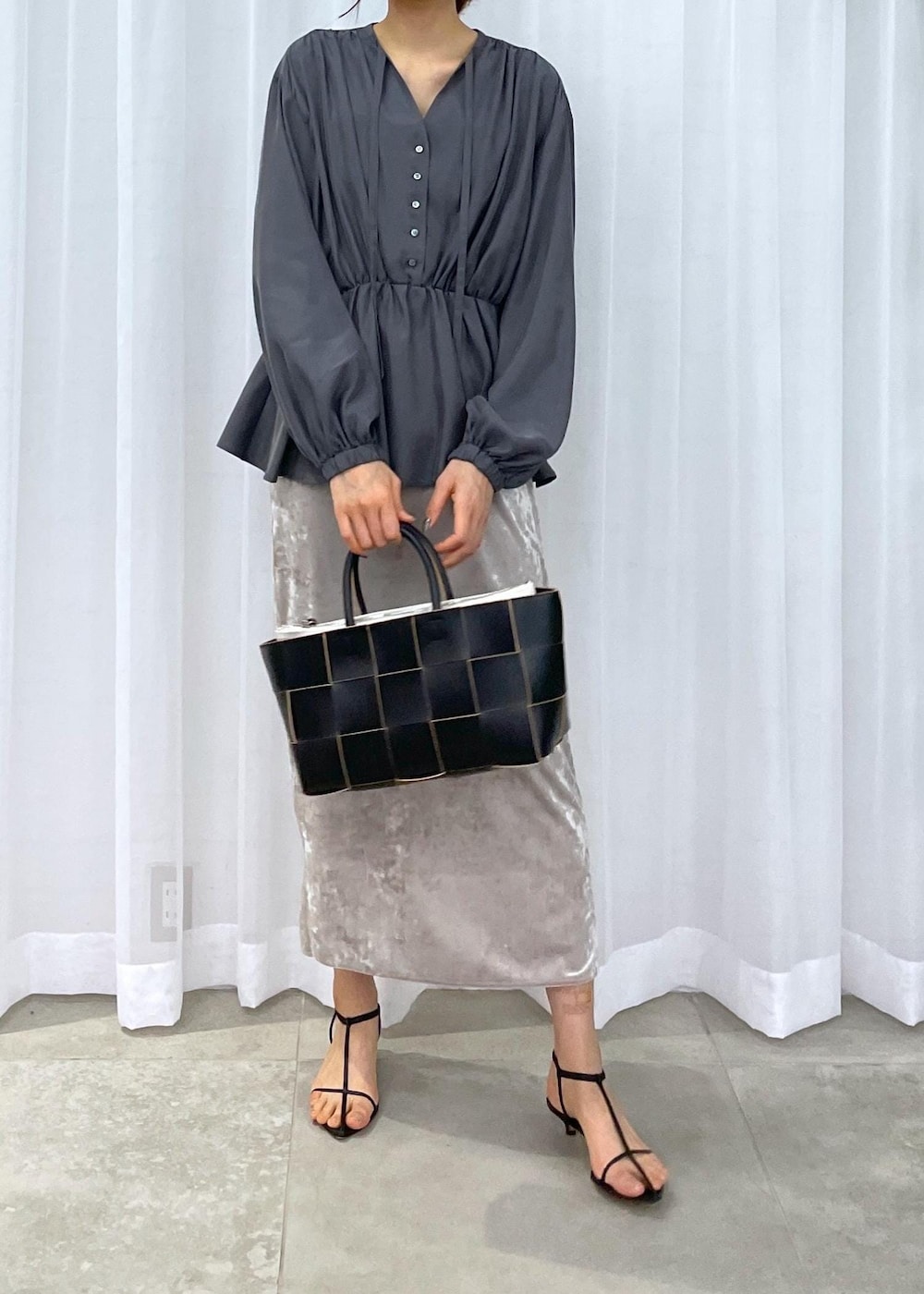 ブラック系のトートバッグ、ベージュ系のスカート、グレー系のシャツ/ブラウスを着用したレディースの冬コーディネートの6枚目の写真