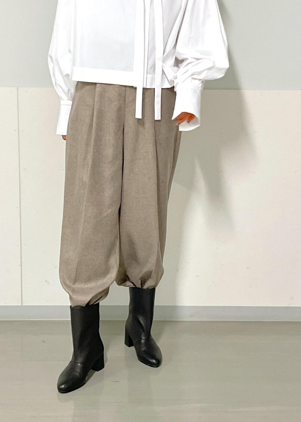 ベージュ系のスラックス、ベージュ系のジャンパースカート、ホワイト系のシャツ/ブラウスを着用したレディースの秋コーディネートの10枚目の写真