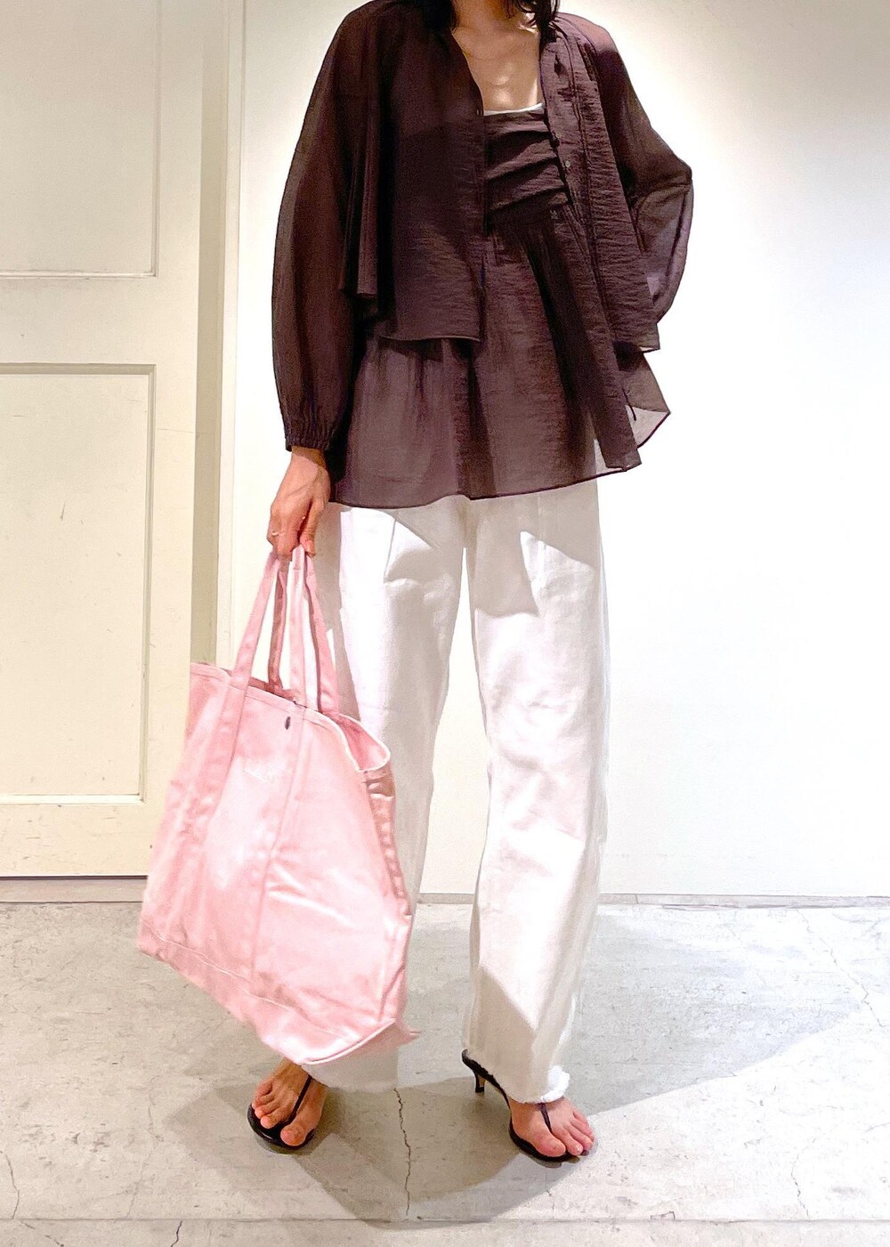 グレー系のタンクトップ、ブラック系のサンダル、ホワイト系のデニムパンツを着用したレディースの夏コーディネートの7枚目の写真