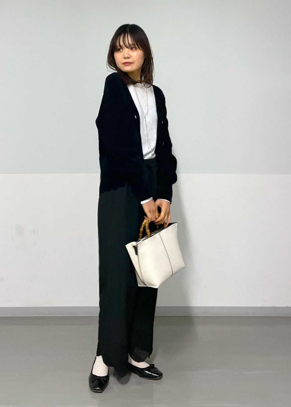 ブラック系のカーディガン/ボレロ、ホワイト系のTシャツ/カットソー、ホワイト系のハンドバッグを着用したレディースの冬コーディネートの6枚目の写真
