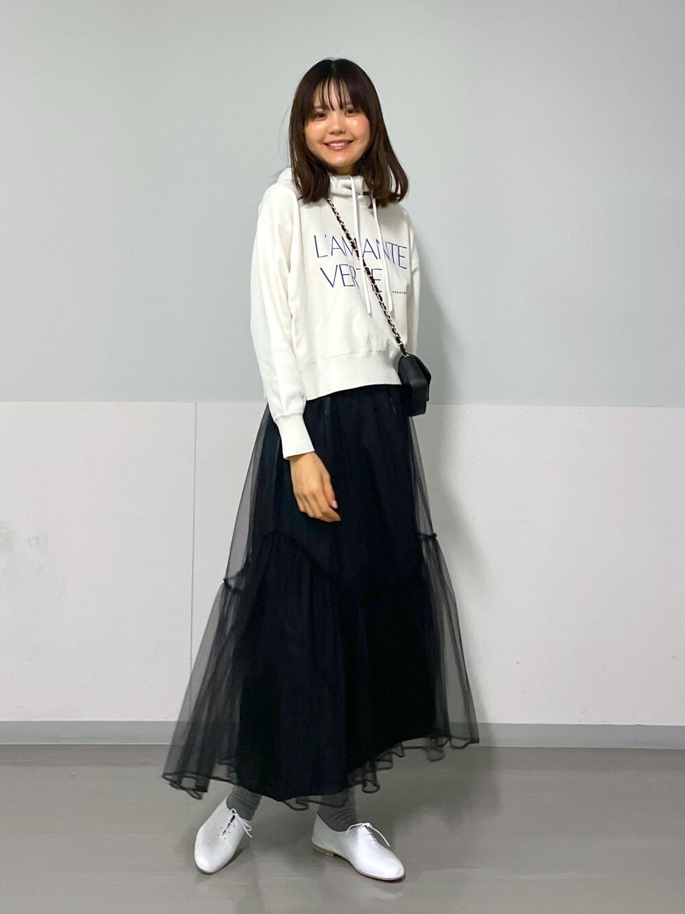 ブラック系のショルダーバッグ、ホワイト系のニット/セーター、ブラック系のスカートを着用したレディースの冬コーディネートの7枚目の写真