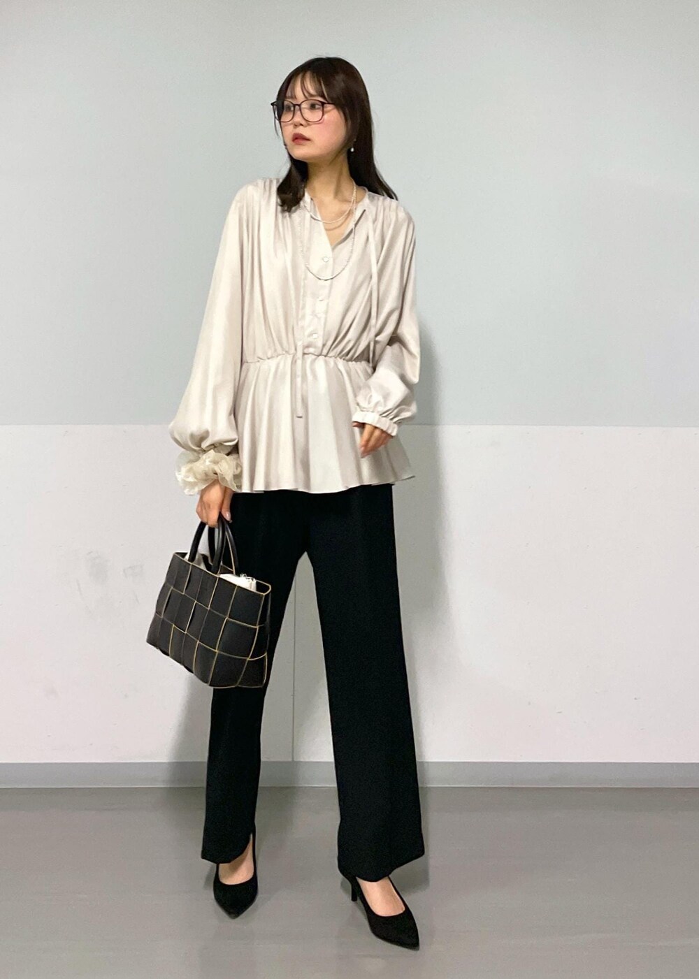 ブラック系のトートバッグ、ブラック系のスラックス、ベージュ系のシャツ/ブラウスを着用したレディースの春コーディネートの2枚目の写真