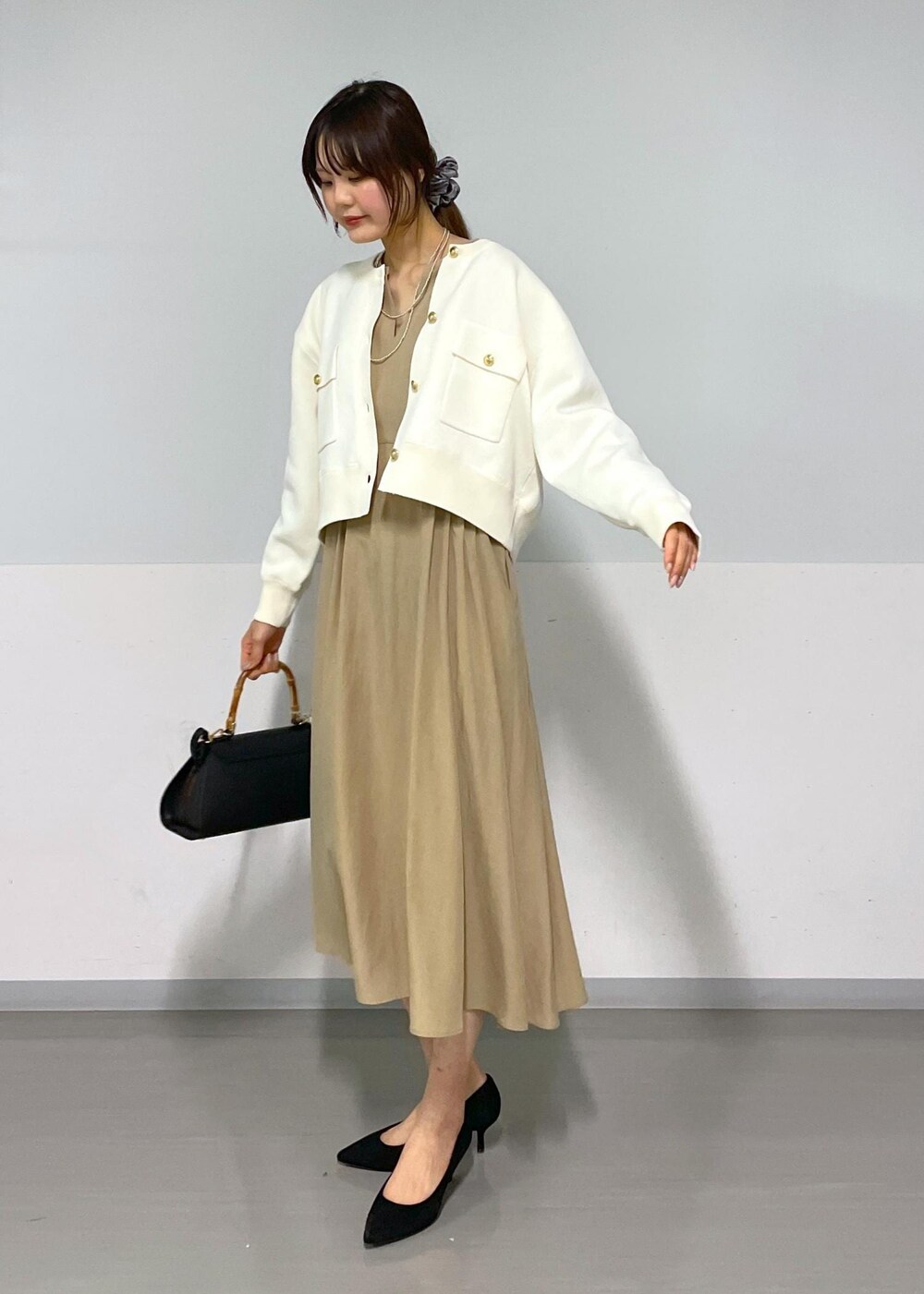 ブラック系のショルダーバッグ、ベージュ系のワンピース、ホワイト系のカーディガン/ボレロを着用したレディースの春コーディネートの3枚目の写真
