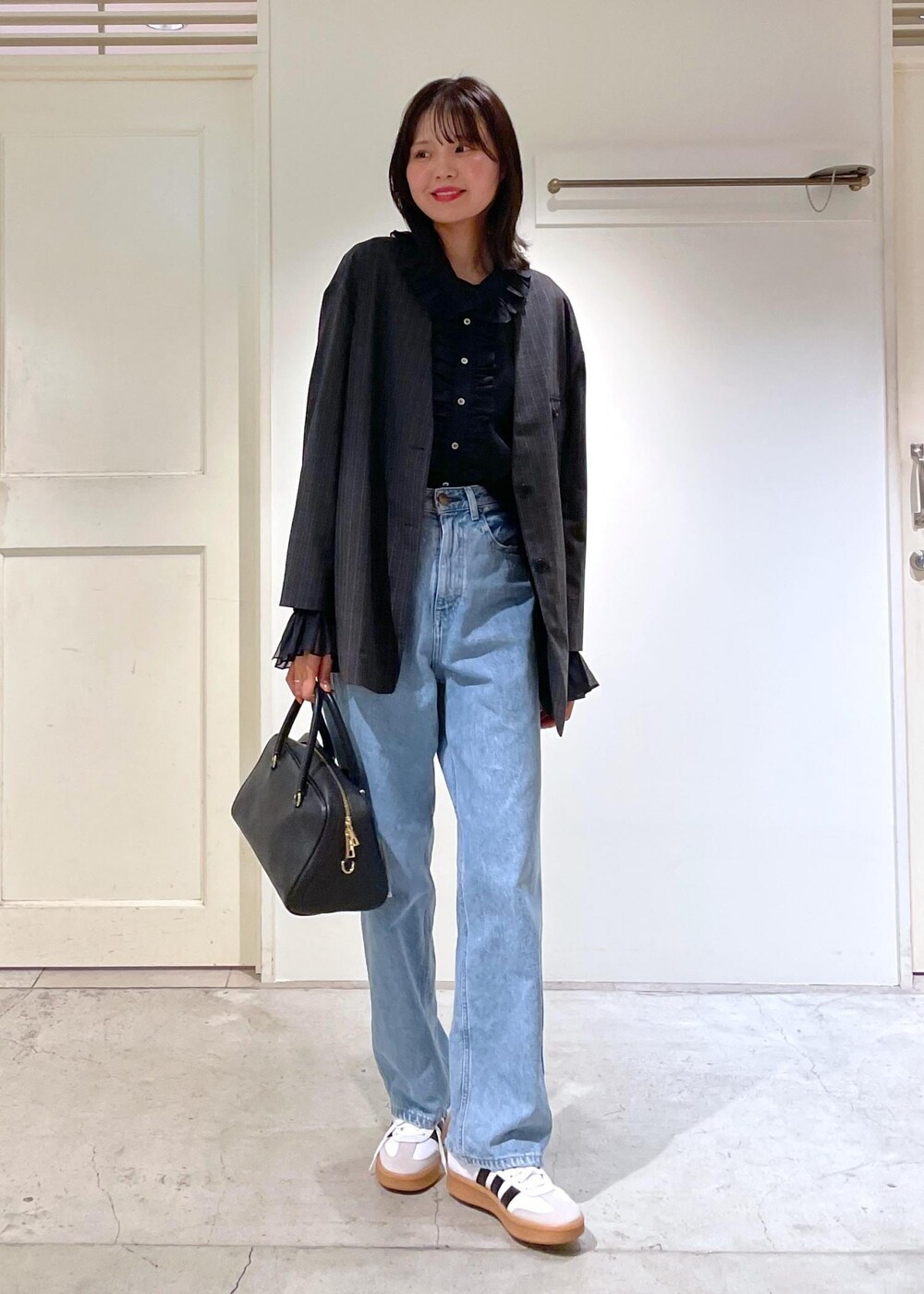 グレー系のノーカラージャケット、ブルー系のデニムパンツ、ブラック系のボストンバッグを着用したレディースの夏コーディネートの10枚目の写真