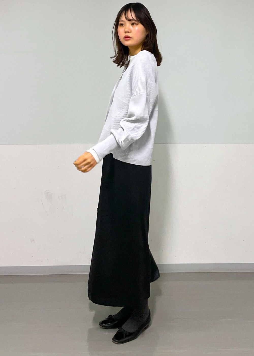 ブラック系のトートバッグ、ホワイト系のTシャツ/カットソー、グレー系のカーディガン/ボレロを着用したレディースの冬コーディネートの5枚目の写真