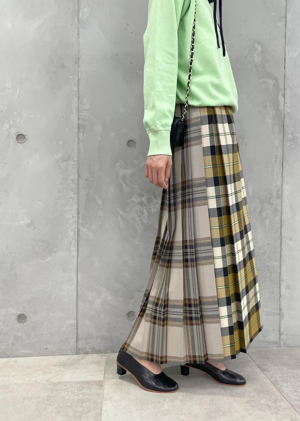 イエロー系のスカート、グリーン系のスウェット、ブラック系のショルダーバッグを着用したレディースの夏コーディネートの5枚目の写真