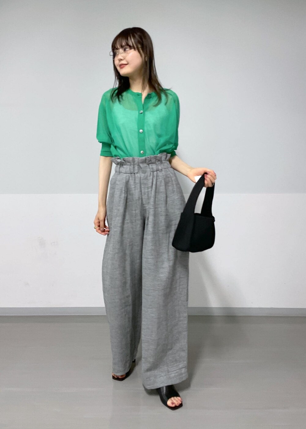 グレー系のタンクトップ、ブラック系のサンダル、グレー系のスラックスを着用したレディースの春コーディネートの3枚目の写真