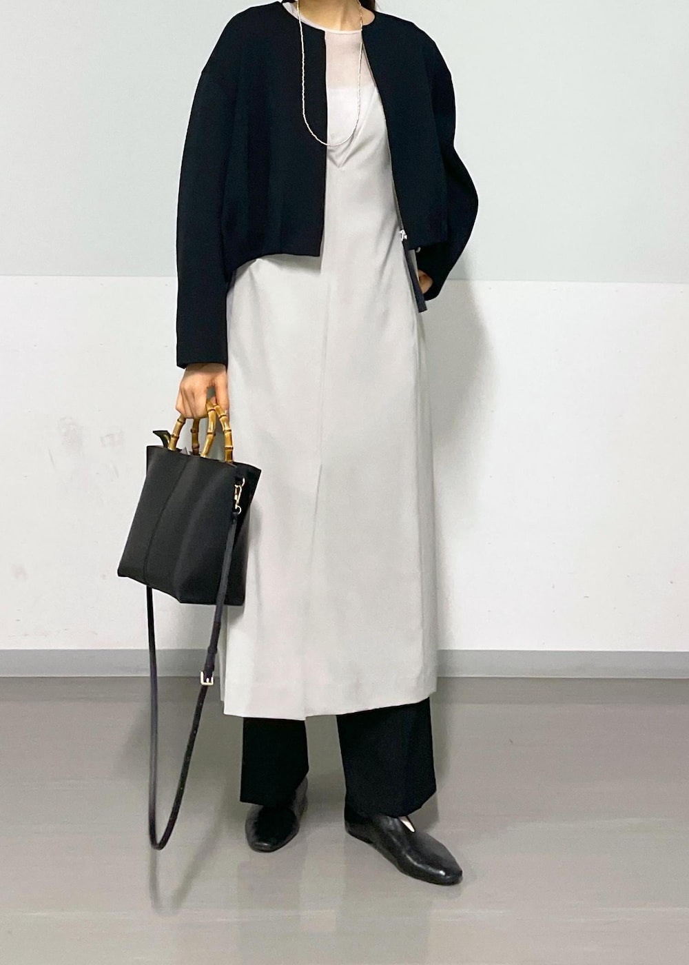 ベージュ系のジャンパースカート、ブラック系のブルゾン、ブラック系のスラックスを着用したレディースの春コーディネートの6枚目の写真