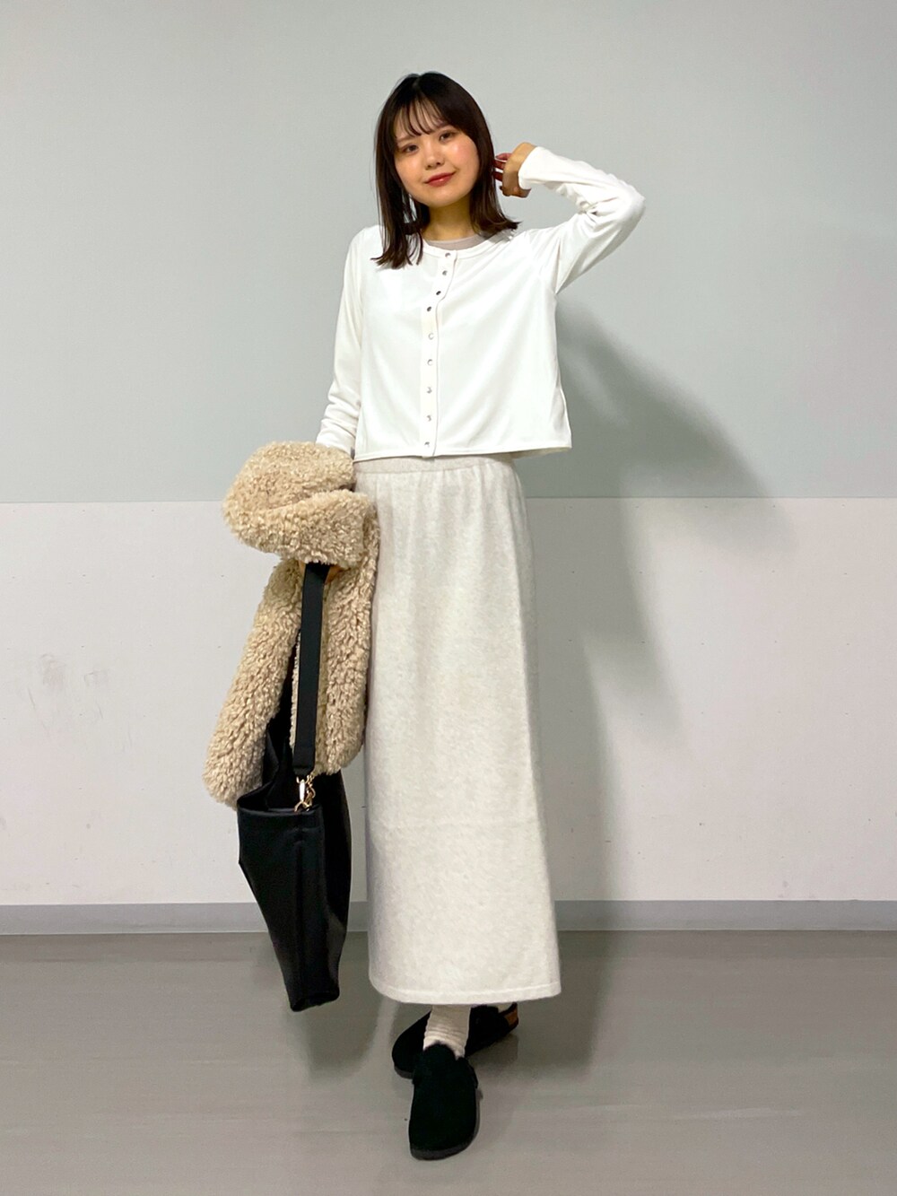 ホワイト系のカーディガン/ボレロ、ベージュ系のベスト、ホワイト系のスカートを着用したレディースの冬コーディネートの3枚目の写真
