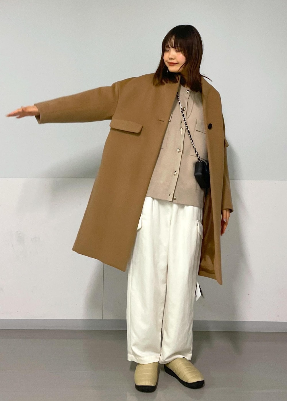 ブラック系のショルダーバッグ、イエロー系のチェスターコート、ベージュ系のカーディガン/ボレロを着用したレディースの冬コーディネートの4枚目の写真