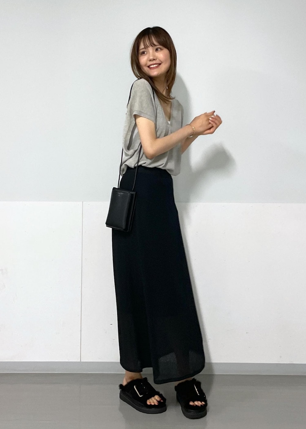 グレー系のタンクトップ、ベージュ系のニット/セーター、ブラック系のスカートを着用したレディースの夏コーディネートの3枚目の写真