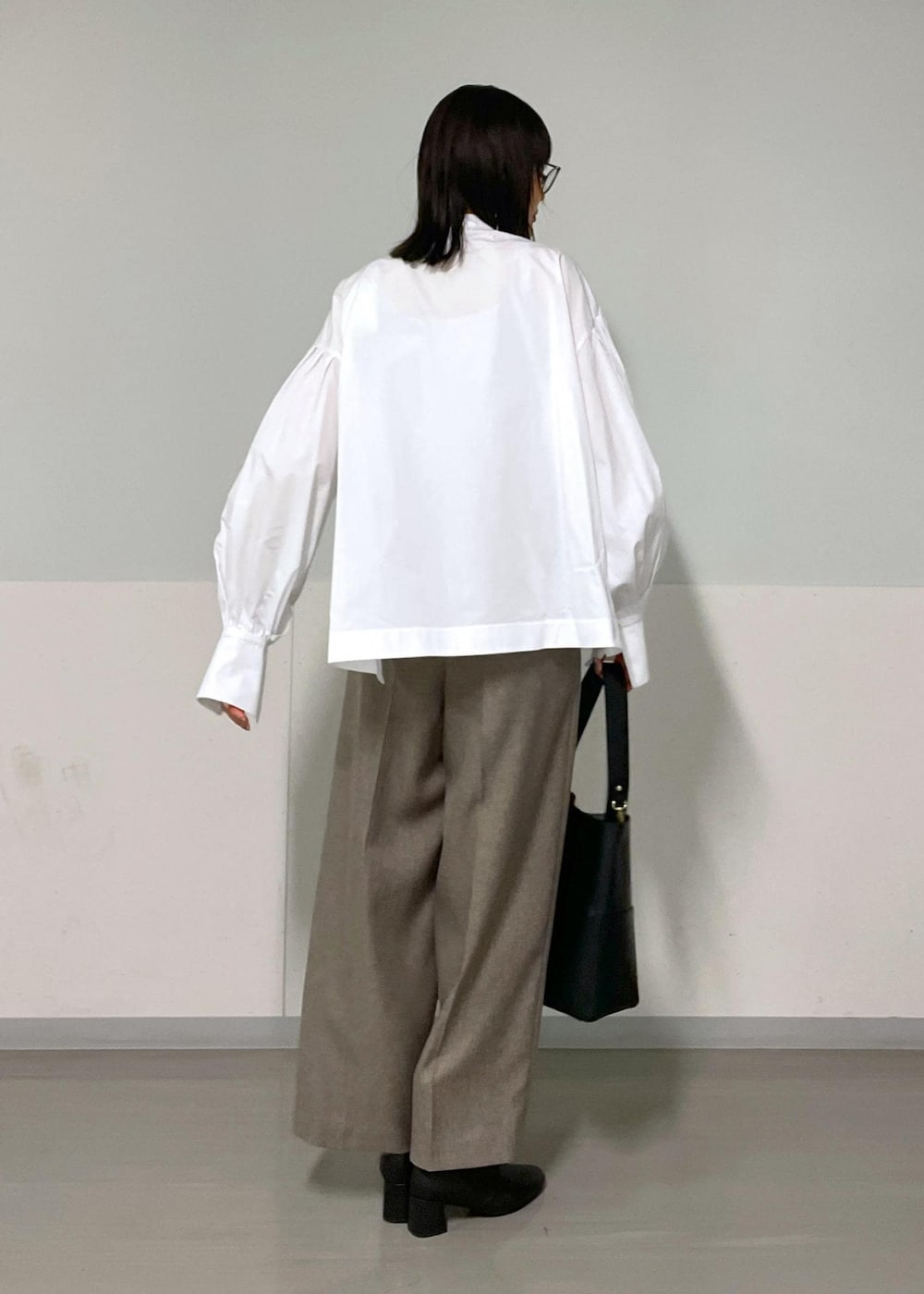 ベージュ系のスラックス、ベージュ系のジャンパースカート、ホワイト系のシャツ/ブラウスを着用したレディースの秋コーディネートの7枚目の写真